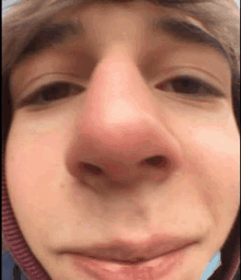 a close up of a person 's face with a red nose and a hat on .