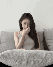 a woman is sitting on a couch covering her mouth with her hand