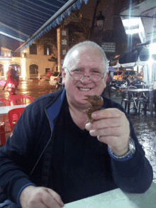 a man holding a piece of food in front of a sign that says " cola qui "