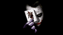 the joker is holding a joker card in his right hand