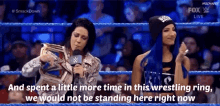 two women are standing in a wrestling ring and one is holding a trophy and the other is talking into a microphone .