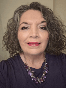 a woman with curly hair and a purple necklace