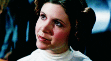 a close up of a woman 's face wearing a white shirt and a bun .