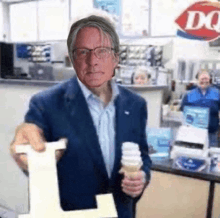 a man in a suit is holding an ice cream cone in front of a dq sign
