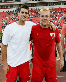 two men are posing for a picture with one wearing a red shirt with a red star on it