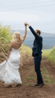 a bride and groom are dancing in a field