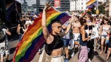 a man is holding a rainbow flag while walking down a street .