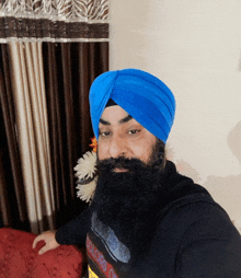 a man with a beard wears a blue turban and a black t-shirt that says colors of