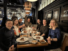 a group of people sit at a table with plates of food