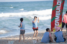 a group of people standing on a beach near a banner that says teambuild