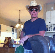 a man wearing a cowboy hat and sunglasses is sitting on a chair