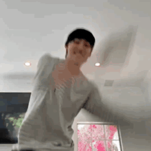 a man in a gray shirt is dancing in a room .