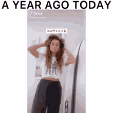 a woman adjusts her hair in front of a surfboard with the caption " a year ago today " on the bottom