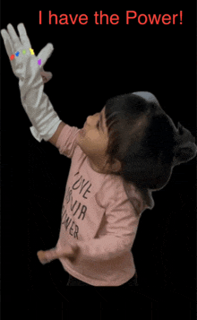 a little girl wearing white gloves and a pink shirt that says i have the power