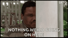 a man is peeking out from behind a post and says `` nothing weird going on here '' .