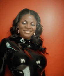 a woman in a black latex outfit is smiling and looking at the camera