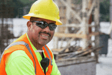 a construction worker wearing a yellow hard hat and sunglasses is smiling for the camera