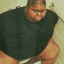 a very fat person is sitting on a toilet .