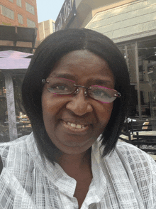 a woman wearing glasses is smiling in front of a sign that says ' a' on it