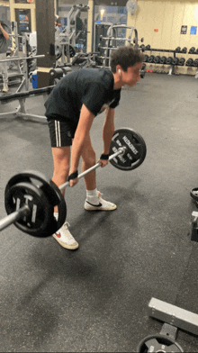 a man is lifting a barbell in a gym with a weight plate that says micro strokes