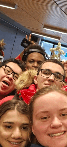 a group of young people are posing for a selfie in a room .