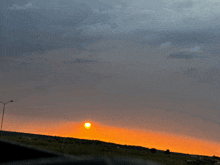 a sunset with a cloudy sky and a few trees in the foreground