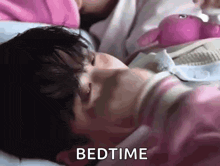 a person is laying in bed with a stuffed animal and the word bedtime is on the bottom .