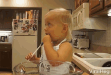 a little girl is brushing her teeth in a kitchen with a measuring cup that says " a 's " on it