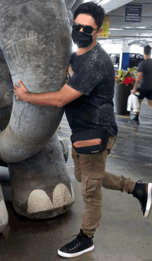 a man wearing a mask hugs a stuffed dinosaur