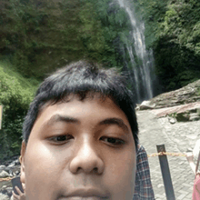 a man is taking a picture of himself in front of a waterfall