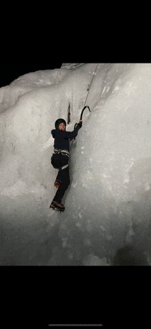 a person is climbing a snow covered cliff with a hammer