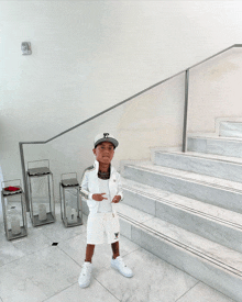 a young boy wearing a white jacket and shorts is standing on a set of stairs