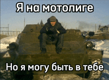 a man sitting on top of a military vehicle with a foreign language caption