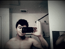 a shirtless man is taking a selfie with a samsung cell phone