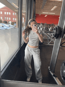 a woman taking a selfie in front of a gym mirror