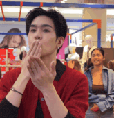 a man in a red jacket is blowing a kiss with his hands