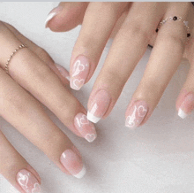 a close up of a woman 's nails with a french manicure and hearts on them