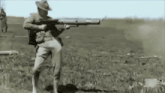 a man in a cowboy hat is holding a large rifle in a field