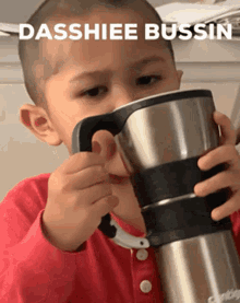 a young boy is drinking from a stainless steel cup with the words dasshiee bussin written above him