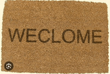 a door mat that says " weclome " in black letters