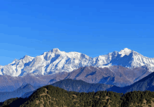 a mountain range with snow on the peaks and a blue sky in the background