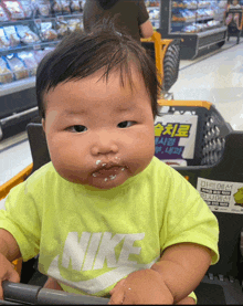 a baby wearing a nike shirt is sitting on a shopping cart