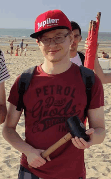 a man wearing a red jupiler hat holds a hammer