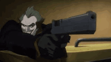 the joker is holding a gun in his hand and pointing it at someone .