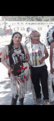 a man and a woman are standing next to each other in native american costumes .