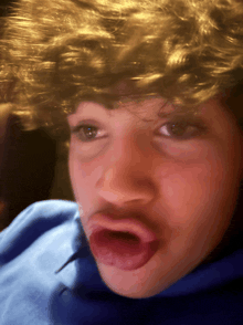 a close up of a person 's face with a blue shirt on