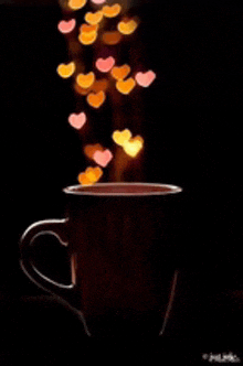 a cup of coffee with hearts coming out of it against a black background