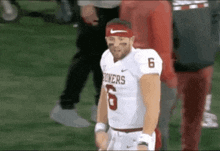 a football player wearing a headband and a jersey with the number 6 on it is standing on the field .