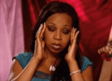 a woman in a blue shirt is covering her ears with her hands
