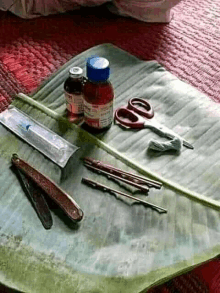 a banana leaf with scissors , a syringe , a razor and a bottle of medicine on it